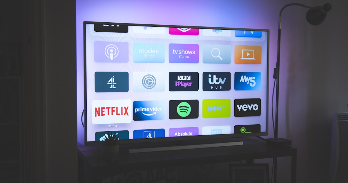 Télécommande de télévision posée sur un canapé, écran en arrière-plan